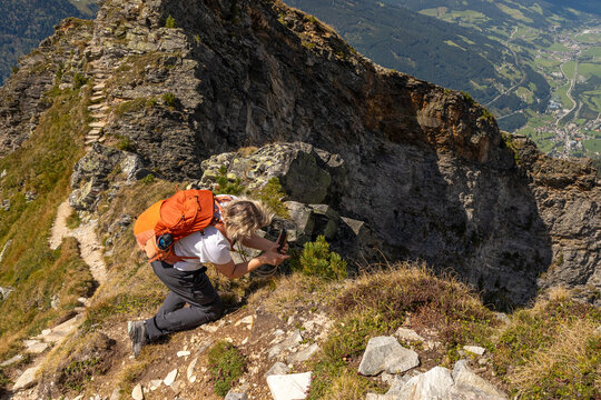 Woman taking photo on steep mountain trail