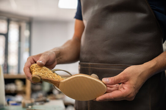 Artisan inspect handmade shoe sole in leather workshop