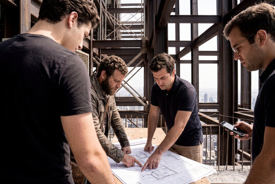 Construction team review blueprint at urban building site