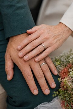 Wedding couple show matching rings and joined hands