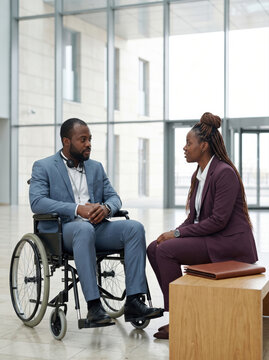 Business colleagues discuss accessibility in modern office lobby