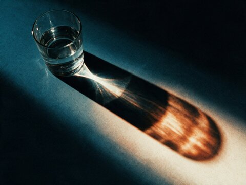 Glass of water casting dramatic light and shadow pattern