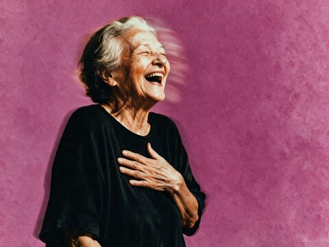 Joyful senior woman laughing against purple studio backdrop