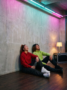 Two dancers warming up on a rehearsal studio floor