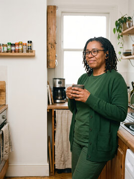 Woman with earbud enjoys coffee during remote work