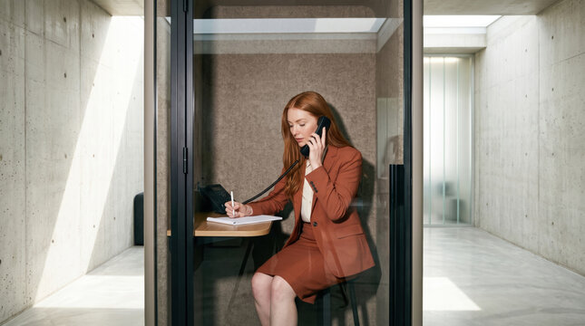 Businesswoman on phone in modern office booth