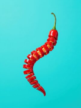 Levitating sliced red chili pepper on turquoise background