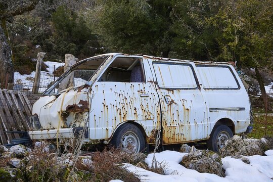 Worn and rusted van in snow-covered and wooded surroundings, wrecked vehicle, Crete, Greek Islands, Greece