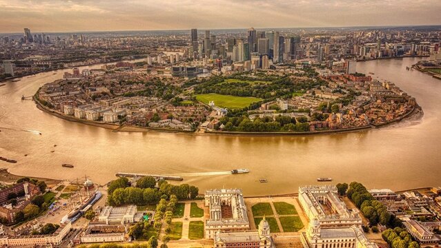 Aerial view of the River Thames curving around the Isle of Dogs with Canary Wharf skyscrapers, Millwall Dock and Mudchute Park, and the City of London skyline in the distance