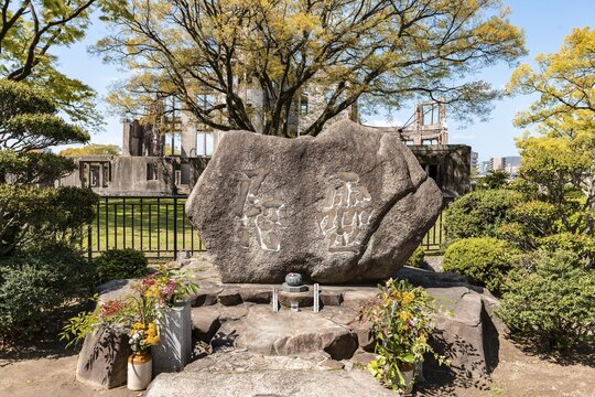 Stone to commemorate the atomic bombs in World War II, atomic bomb dome at the back, peace monument, Hiroshima Peace Park, Hiroshima, Japan
