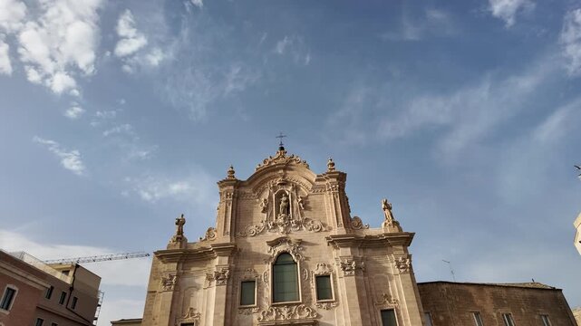  Elegant tilt shot of the 18th-century Baroque facade of San Francesco d'Assisi church in the historic center of Matera. Sunny day footage highlighting the limestone architecture and statues. 