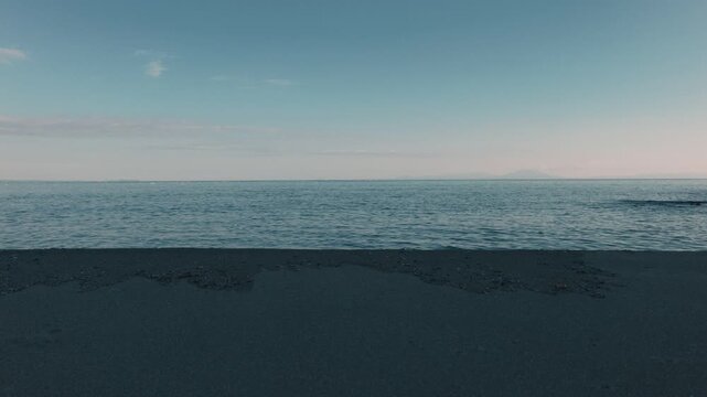 Gentle Waves Lapping Against a Blue-Gray Sandy Beach Beneath a Gradient Sky