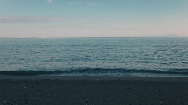 Gentle Waves Lapping Against a Blue-Gray Sandy Beach Beneath a Gradient Sky