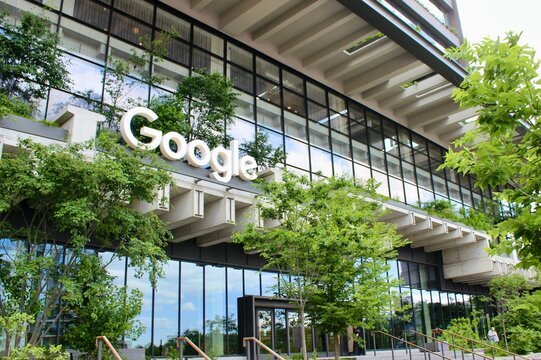 Google sign surrounded by growing trees and plants on facade of headquarters at 550 Washington Street in Hudson Square, Manhattan, New York City