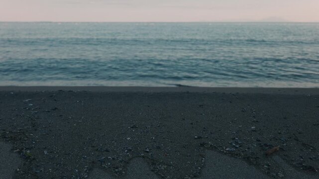 Gentle Waves Lapping Against a Blue-Gray Sandy Beach Beneath a Gradient Sky