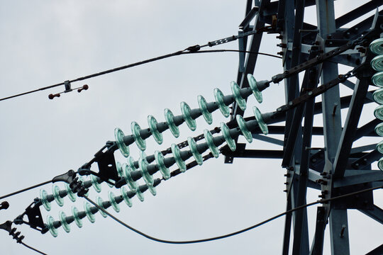 Detailed view of steel lattice pylon body showing multiple glass insulator strings and parallel high voltage wires