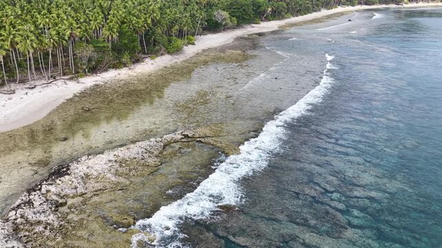 Calm seas bathe the beautiful coastline of the remote Maju Island in the Molucca Sea, Indonesia. A rugged, rocky reef surrounds this tropical paradise which few people ever visit.