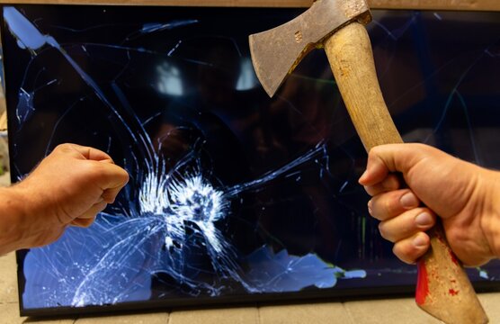 Angry person destroying flat screen tv with an axe