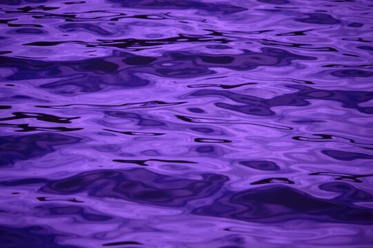 Purple water surface ripples with violet liquid reflections on lake