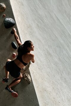 Woman climbing minimalist indoor bouldering wall in modern gym