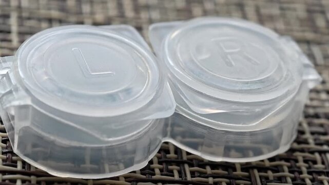 Two plastic containers sit on a woven table