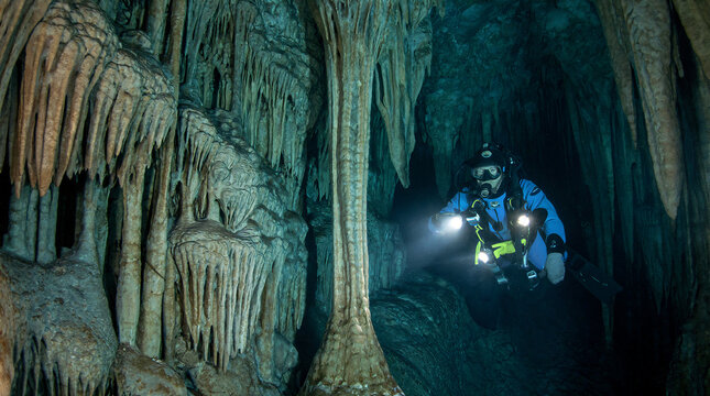 Underwater cave exploration, sixty year old man in a drysuit navigates a submerged cavern