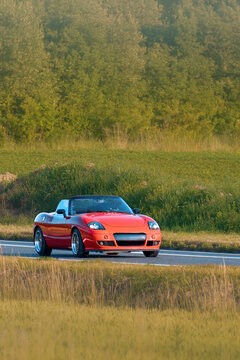 Open roof convertible car cruising rural landscape