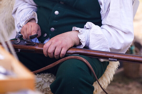 Musket cleaning at a Napoleonic era reenactment camp. Close-up of a person in historical costume cleaning a musket during a living history reenactment event.