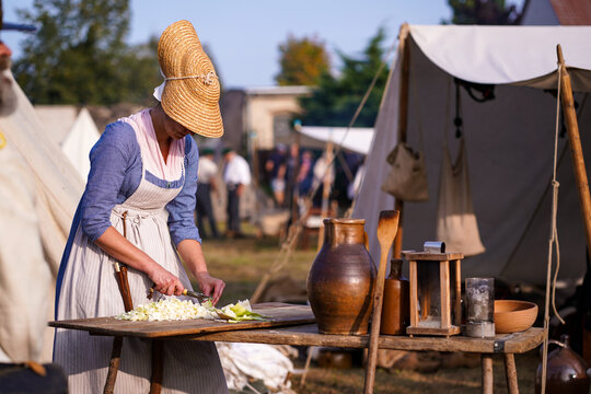 Woman cooking at a Napoleonic era reenactment camp. Female reenactor in early 19th century dress preparing cabbage at camp during the 1813 Battle of Wartenburg reenactment.
