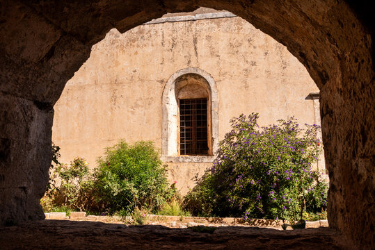 Arkadi, Greece - October 03, 2026 - Courtyard View of Church Window Framed by Stone Archway at Arkadi Monastery