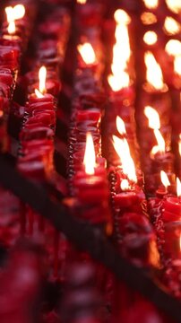 Rows of burning candles in a catholic church. Slow Motion vertical video.