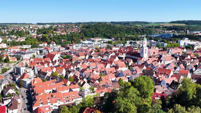 Malerische Panorama-Luftaufnahme von Biberach an der Ri&szlig; mit der historischen Altstadt, markanten Kircht&uuml;rmen und herbstlichen B&auml;umen unter blauem Himmel.