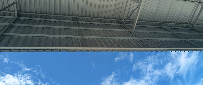 Metal sheet roof curve on blue sky. Modern construction, Metal ribbed arch span roof covering, Large building roof. not ai