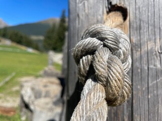Close-up of rope knot tied to wooden post outdoors © Luana Ciambellini