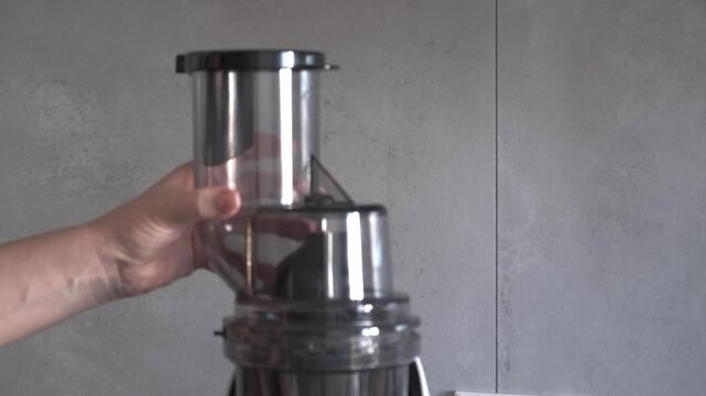 Woman hands installing a plastic lid hopper on a slow juicer machine, assembling a modern kitchen appliance for fresh juice