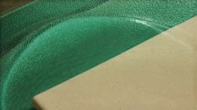 Emerald caustic pattern drifting across ceramic