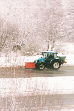 Winter tractor clearing snow on icy roadway