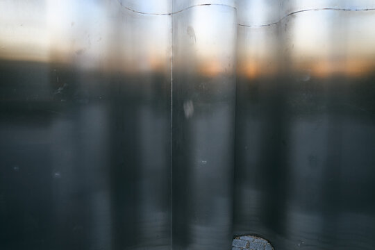 Abstract metallic wall with soft sunset light reflections and smooth curved surface texture