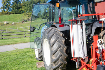 Agricultural tractor with equipment parked on rural farm pasture © Maxwell