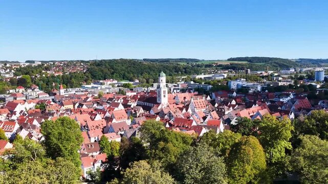 Malerische Panorama-Luftaufnahme von Biberach an der Ri&szlig; mit der historischen Altstadt, markanten Kircht&uuml;rmen und herbstlichen B&auml;umen unter blauem Himmel.