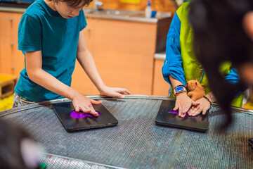 Boy experimenting with hands on science activity in a learning space indoors with interactive...