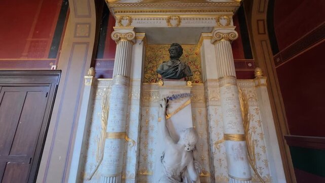 Marble war memorial with a bronze bust of the painter Henri Regnault, a female figure reaching up with flowers and gold trimmed Ionic columns, low angle, Ecole des Beaux Arts, Paris, France