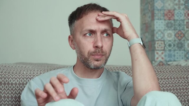 Stressed man fidgeting and thinking through difficult decision at home with anxiety, tension, uncertainty, overthinking and concentration on serious problem.