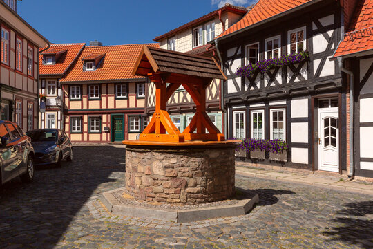 Picturesque cobblestone street with traditional half-timbered houses, colorful flowers and an old stone well in Wernigerode, Germany.