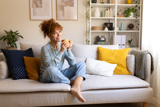 Woman drinking coffee relaxing on sofa at home