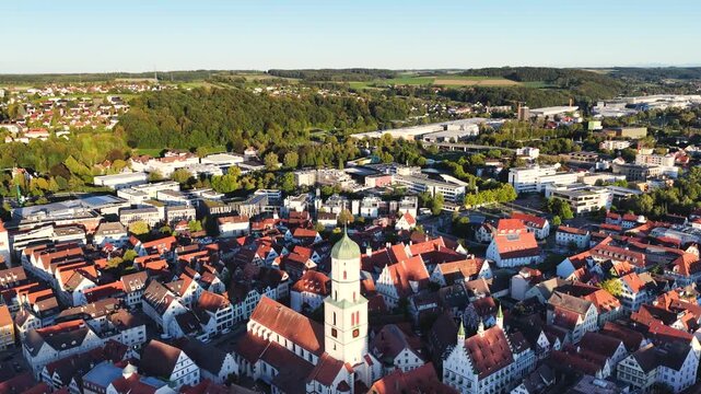 Malerische Panorama-Luftaufnahme von Biberach an der Ri&szlig; mit der historischen Altstadt, markanten Kircht&uuml;rmen und herbstlichen B&auml;umen unter blauem Himmel.