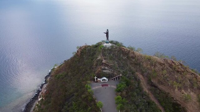Aerial lowering over Cristo Rei statue of Jesus Christ overlooking ocean in Dili, Timor-Leste, Southeast Asia