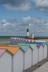 Fototapeta premium Views of ocean beach and colourful beach huts or cabins in Le Treport, seaside resort in Normandy, France, with white cliffs along English Channel, travel destination in France