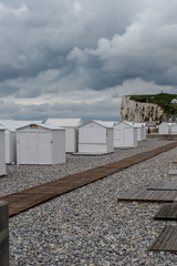 Fototapeta premium White bath huts in Mers-les-Bains, seaside town with 19th-century sea-bathing villas with colorful wooden balconies and white chalk cliffs, tourists destination in France