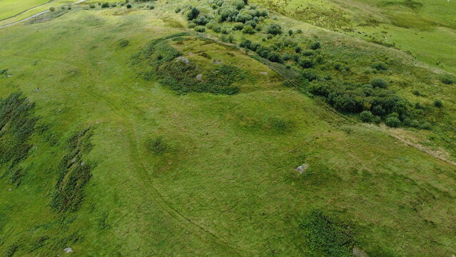 Aerial drone view of Beattock hill fort earthworks and ramparts on a green hillside, Dumfries and Galloway, Scotland, UK
